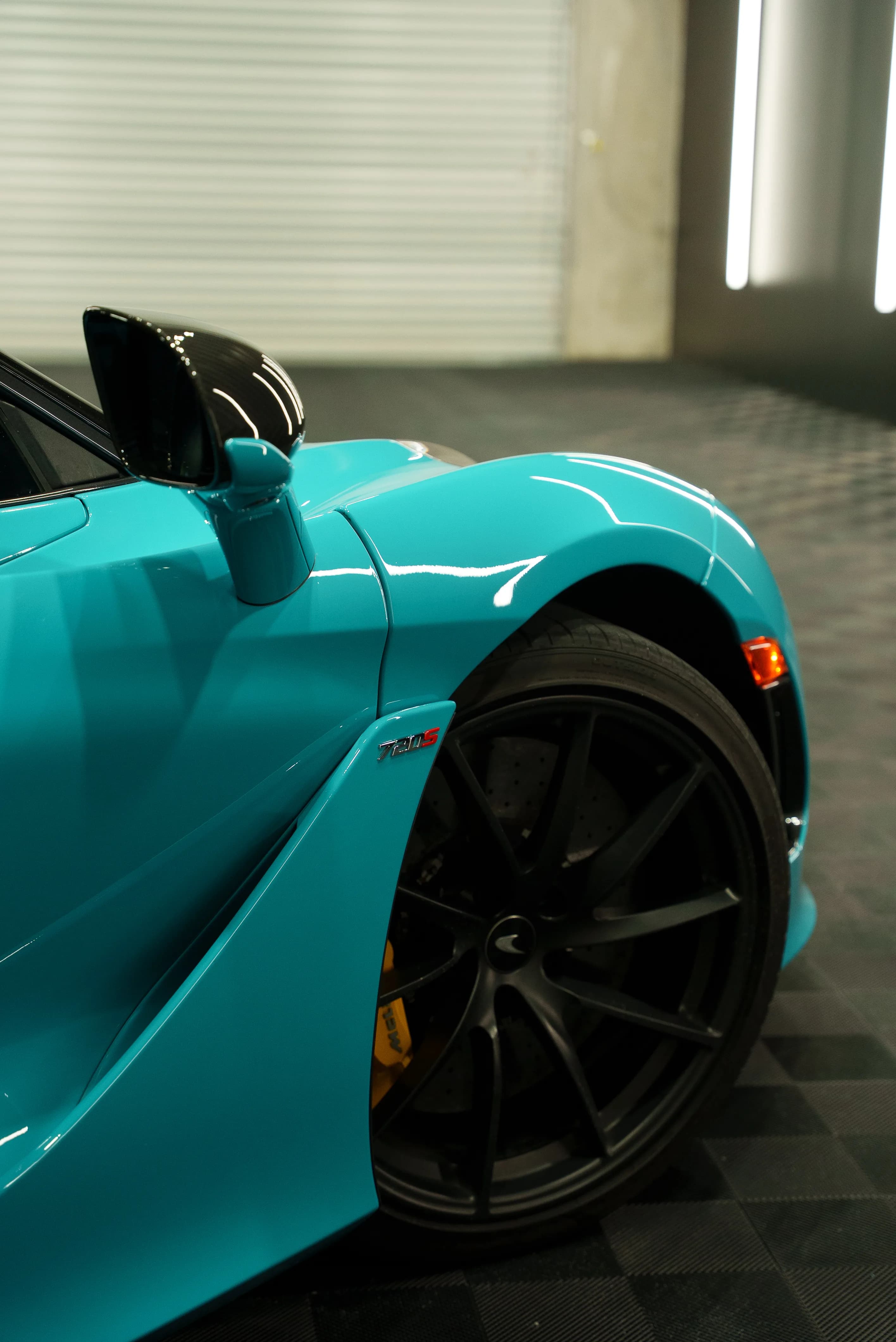 Wheel and fender detail on a teal-wrapped McLaren 720S